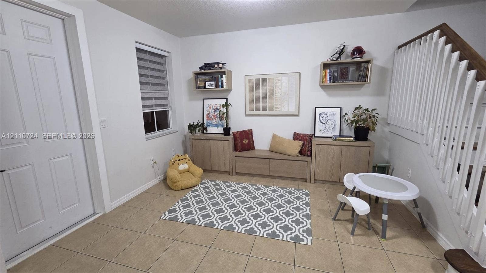 10846 SW 240th Lane, Homestead, FL 33032 Neutral-toned tile flooring, built-in wooden cabinetry featuring a central bench seat, floating wall-mounted shelving, and a wooden staircase handrail