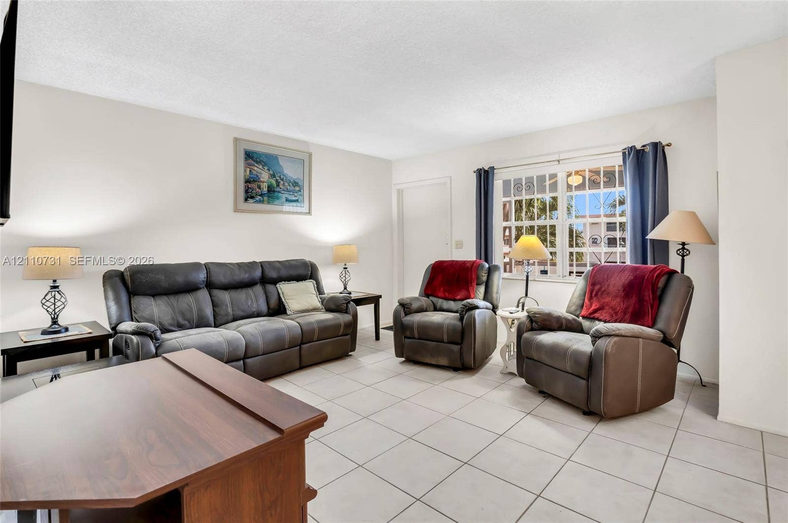 Living area featuring ceramic tile flooring, neutral wall tones, and large windows with decorative muntin grids