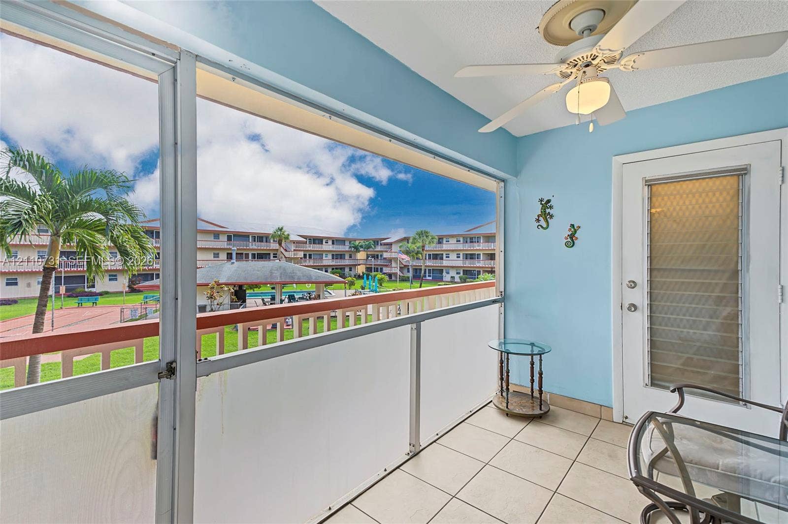 Screened-in balcony featuring tile flooring, ceiling fan, and metal-framed railing