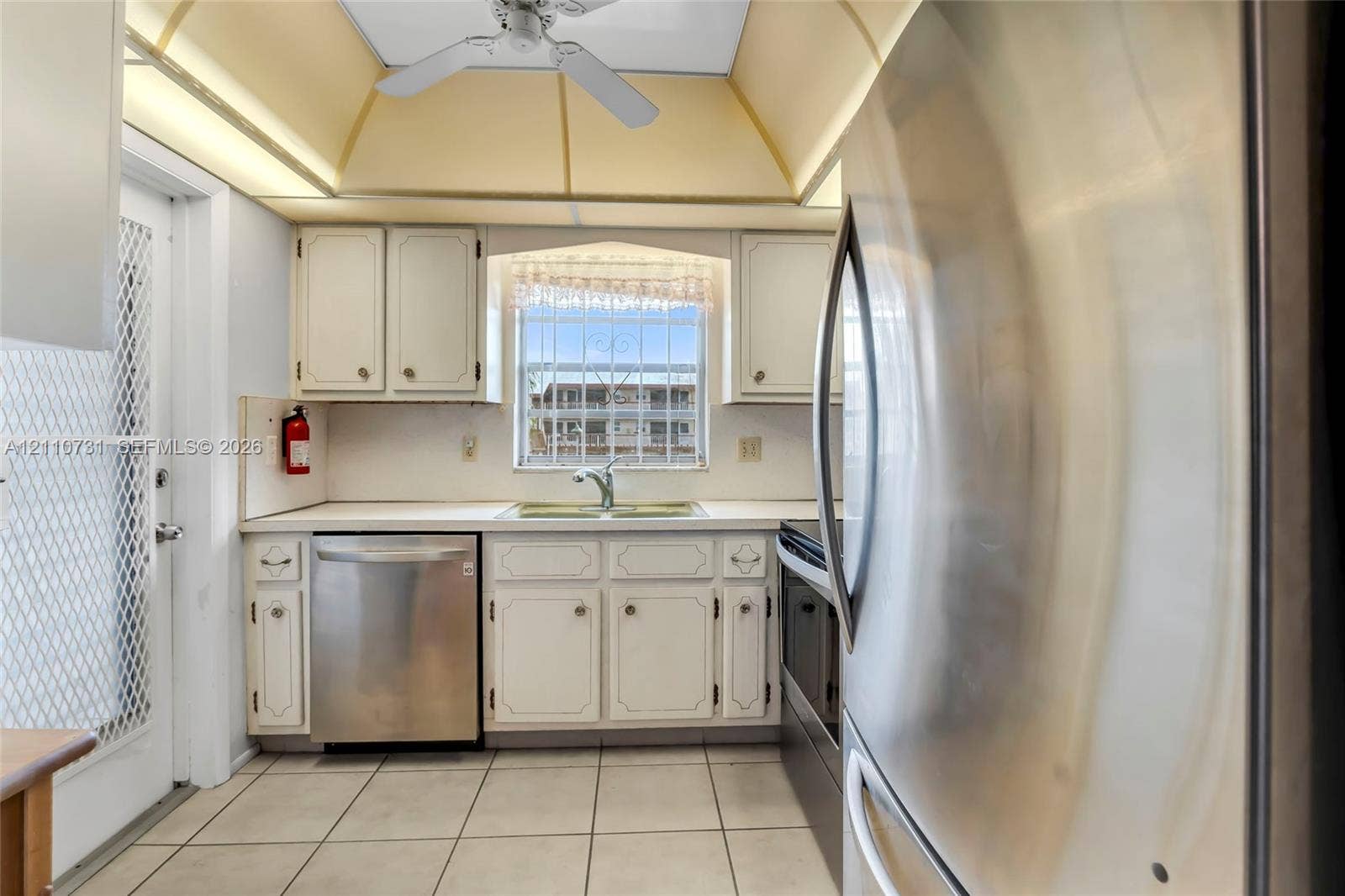 Kitchen featuring stainless steel appliances, recessed ceiling lighting, vaulted ceiling, and ceramic tile flooring