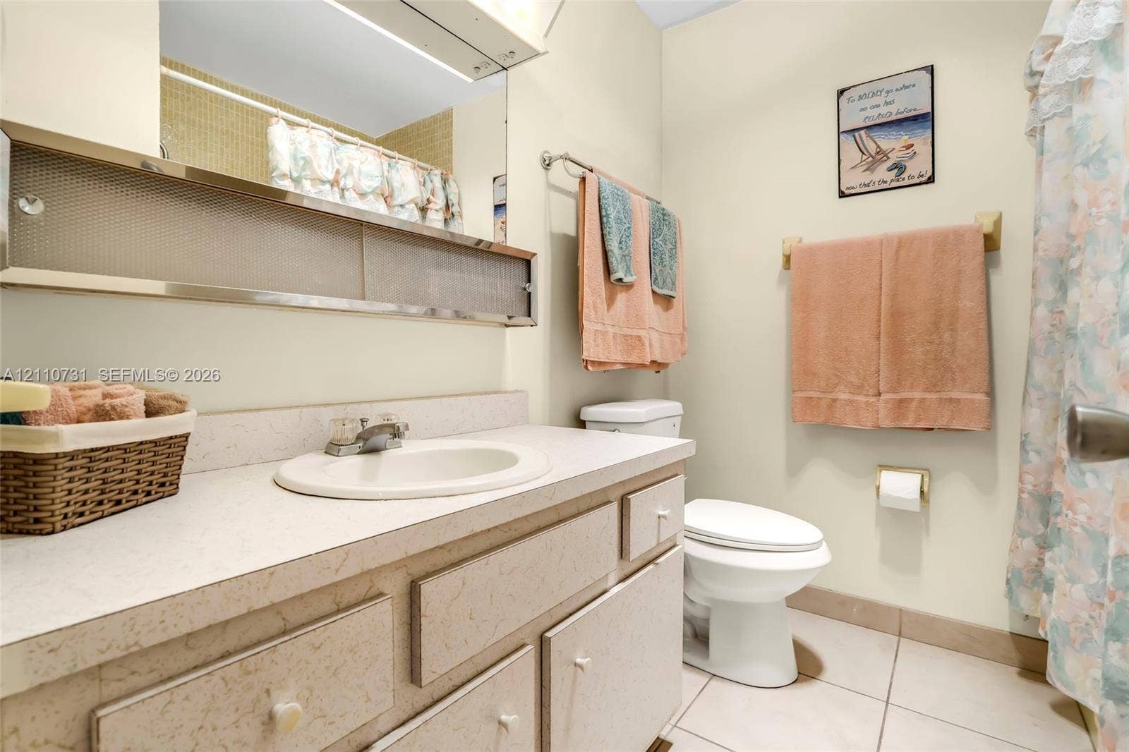 Bathroom featuring a solid-surface vanity countertop with an integrated basin, metal-framed mirrored cabinetry, and ceramic tile flooring