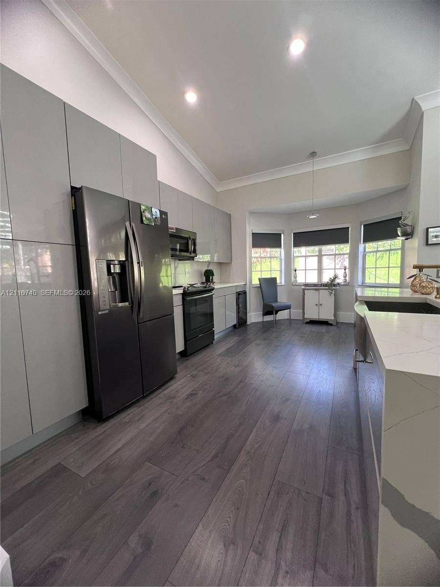 Modern kitchen featuring high-gloss cabinetry, wood-finish flooring, a quartz countertop island, recessed lighting, and a bay window