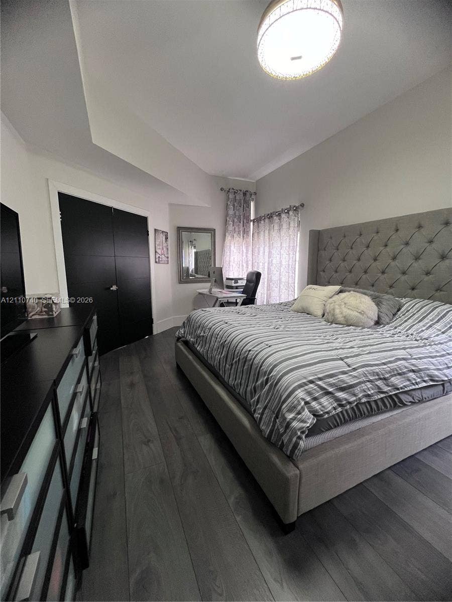 Wood-finish flooring, high ceilings with recessed architectural detail, and double-panel doors featuring a matte finish