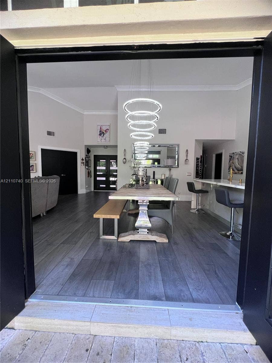Interior space featuring wood-finish flooring, vaulted ceilings, and a multi-tiered circular pendant light fixture