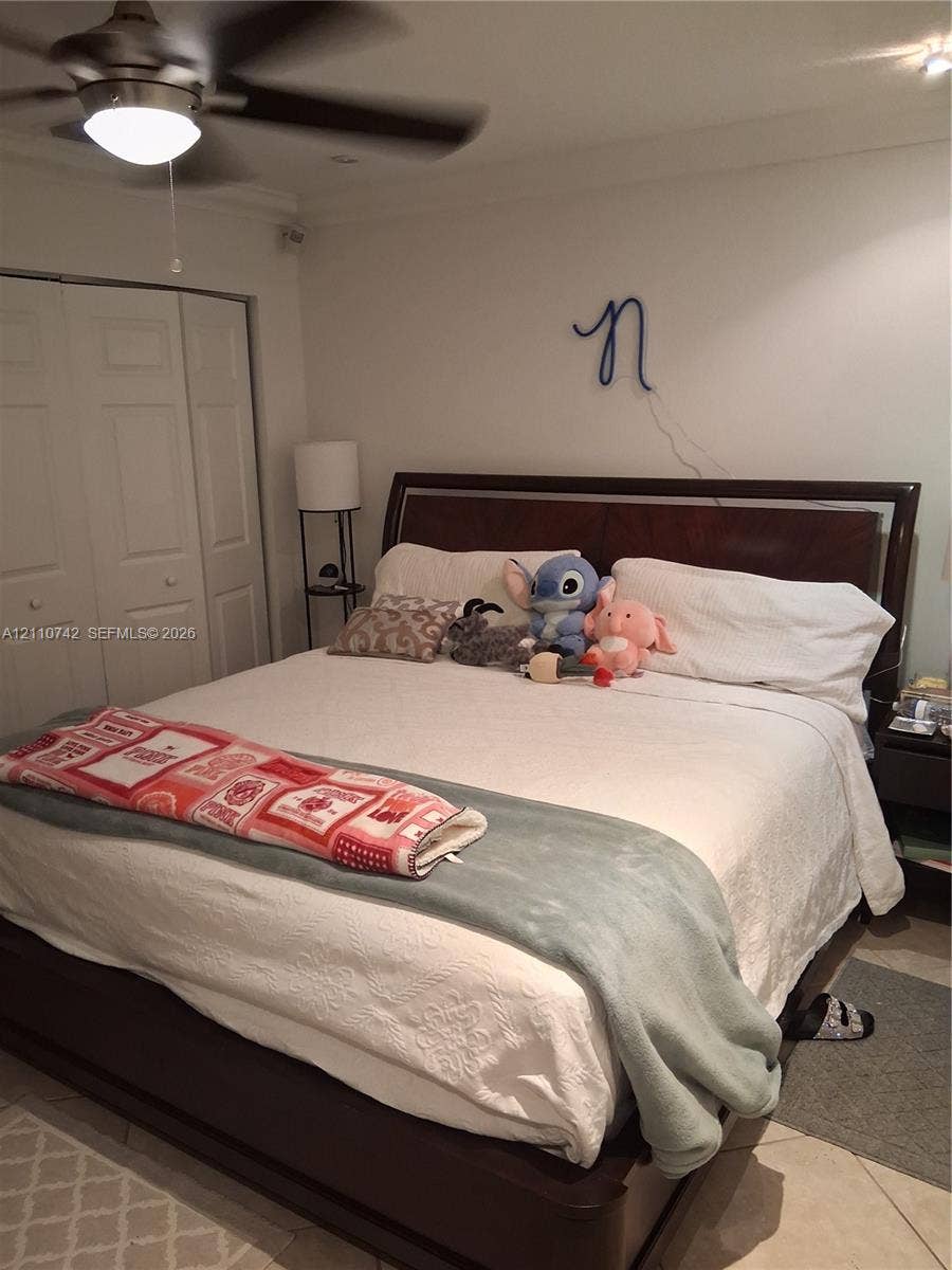 Room featuring tile flooring, ceiling fan with integrated lighting, and bi-fold closet doors