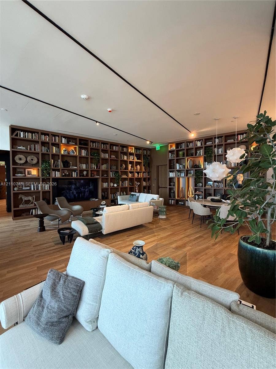 Extensive floor-to-ceiling custom built-in shelving, wood-finish flooring, and recessed linear track lighting