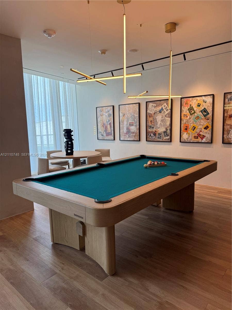 Modern linear pendant lighting, wood-finish flooring, and floor-to-ceiling window treatments