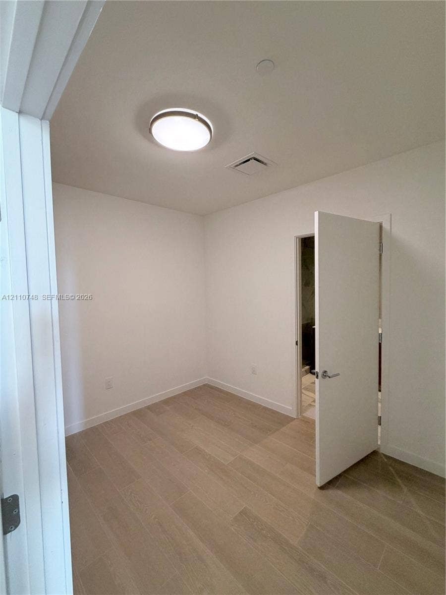Neutral wall tones, wood-finish flooring, and a flush-mount ceiling light fixture
