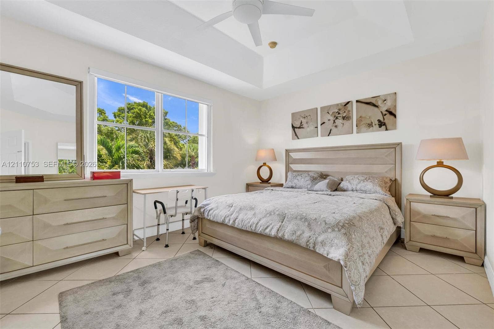 Tray ceiling featuring a central ceiling fan, large windows, and tile flooring