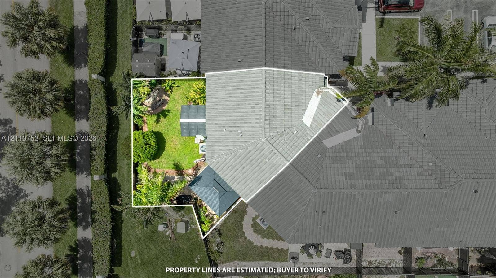 Aerial perspective highlighting a fenced-in yard, paved patio area, green space, and tile roofing