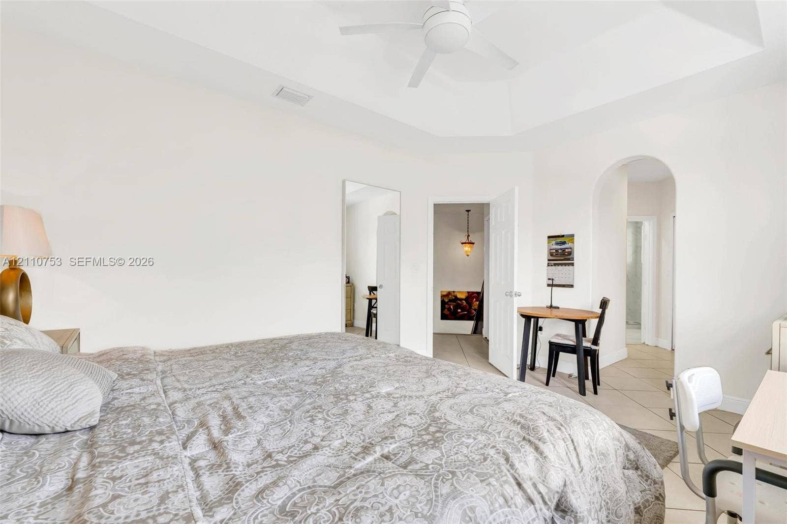 Room featuring a tray ceiling, ceiling fan, ceramic tile flooring, and arched entryway