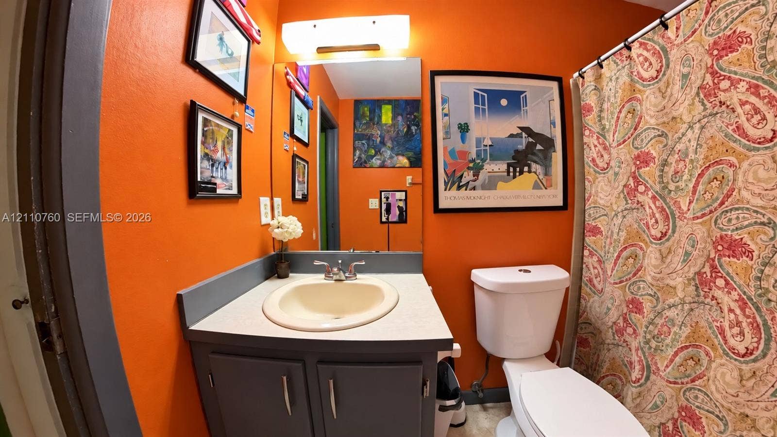 Bathroom featuring a gray vanity cabinet, integrated sink, countertop, and an above-mirror light fixture