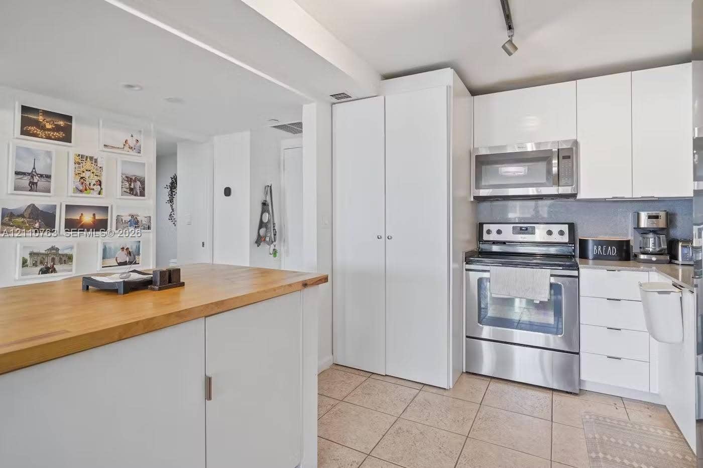 1901 Brickell Avenue, #B1706, Miami, FL 33129 Kitchen featuring white flat-panel cabinetry, stainless steel appliances, a butcher block-topped island, and tile flooring