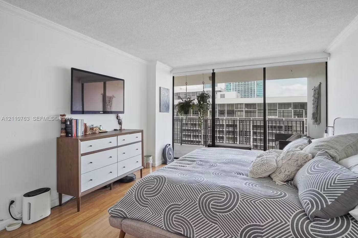 1901 Brickell Avenue, #B1706, Miami, FL 33129 Floor-to-ceiling windows featuring access to a private balcony, wood-finish flooring, and crown molding