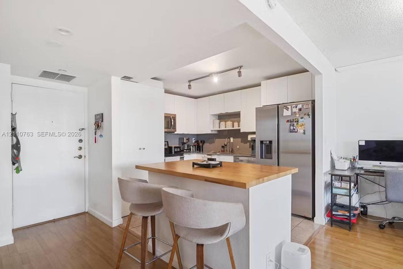 1901 Brickell Avenue, #B1706, Miami, FL 33129 Kitchen featuring white cabinetry, wood-finish flooring, a central island with a wood countertop, stainless steel refrigerator, and recessed track lighting