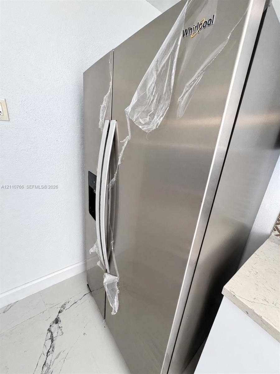 Stainless steel Whirlpool refrigerator featuring an integrated door water and ice dispenser