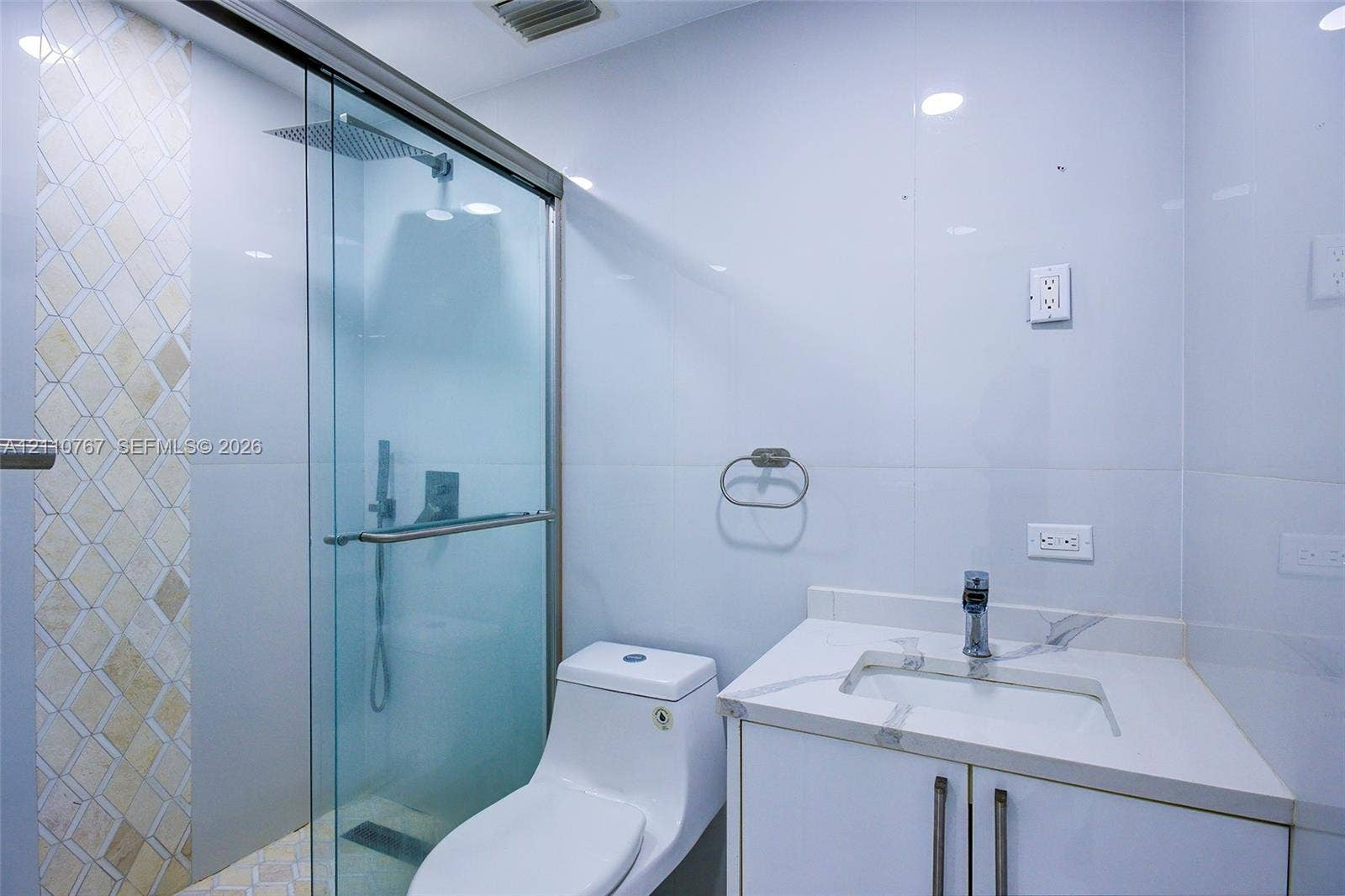 5305 Cleveland Road, Delray Beach, FL 33484 Walk-in glass shower enclosure with a rainfall showerhead, white vanity cabinet with an integrated rectangular sink, wall-mounted faucet, and decorative tiled shower wall accent
