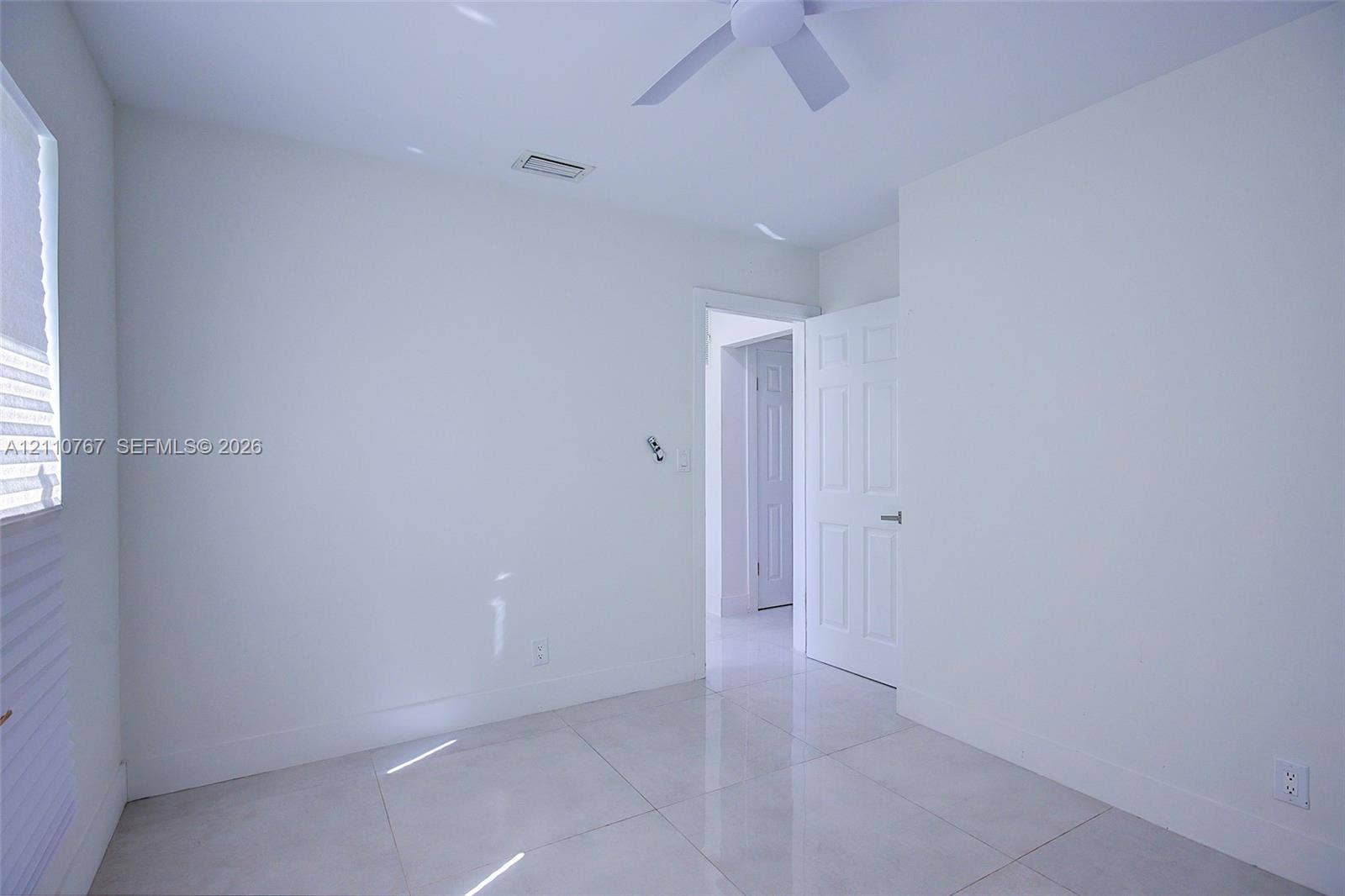 5305 Cleveland Road, Delray Beach, FL 33484 Interior room featuring large-format tile flooring, a neutral white color palette, and a white ceiling fan with integrated lighting