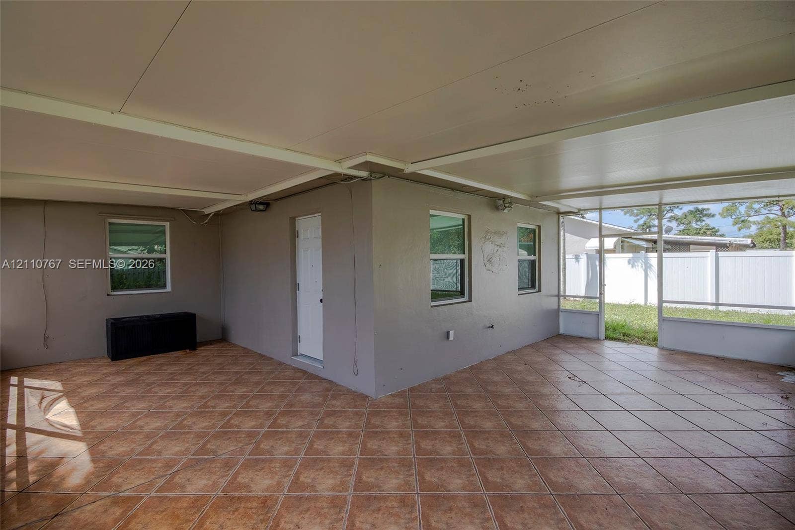 5305 Cleveland Road, Delray Beach, FL 33484 Covered patio featuring ceramic tile flooring, solid wall construction, white exterior door, and screen-enclosed sections