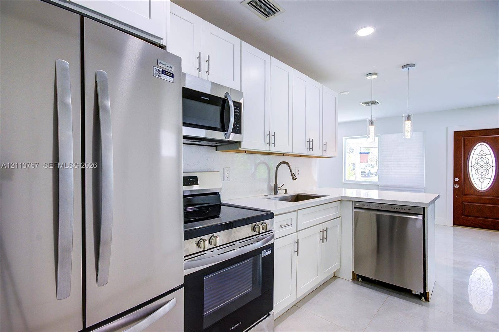 5305 Cleveland Road, Delray Beach, FL 33484 Kitchen featuring white shaker-style cabinetry, stainless steel appliances, solid-surface countertops, dual pendant lighting, and polished floor tile