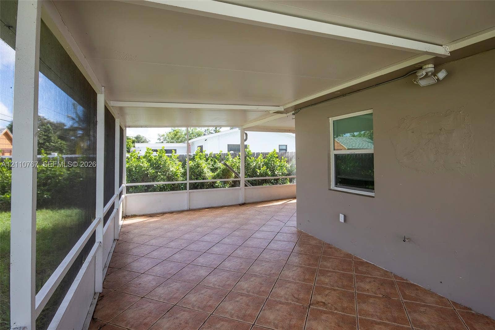 5305 Cleveland Road, Delray Beach, FL 33484 Screened-in patio featuring a solid roof covering, diamond-patterned tile flooring, and perimeter screening