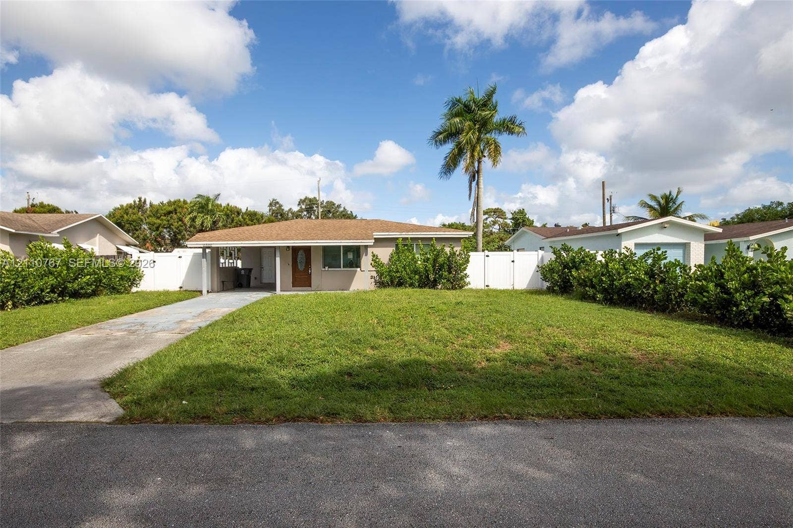 5305 Cleveland Road, Delray Beach, FL 33484 Single-story residence featuring a low-slope roof, covered entryway, concrete driveway, and full-perimeter vinyl privacy fencing