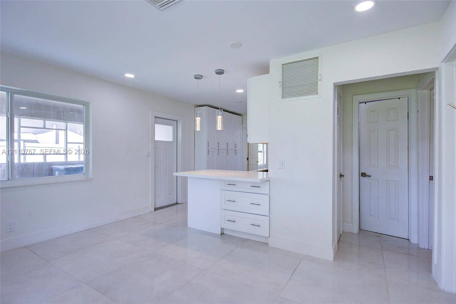 5305 Cleveland Road, Delray Beach, FL 33484 Interior space featuring large-format tile flooring, recessed lighting, built-in cabinetry with a white peninsula, and dual pendant light fixtures