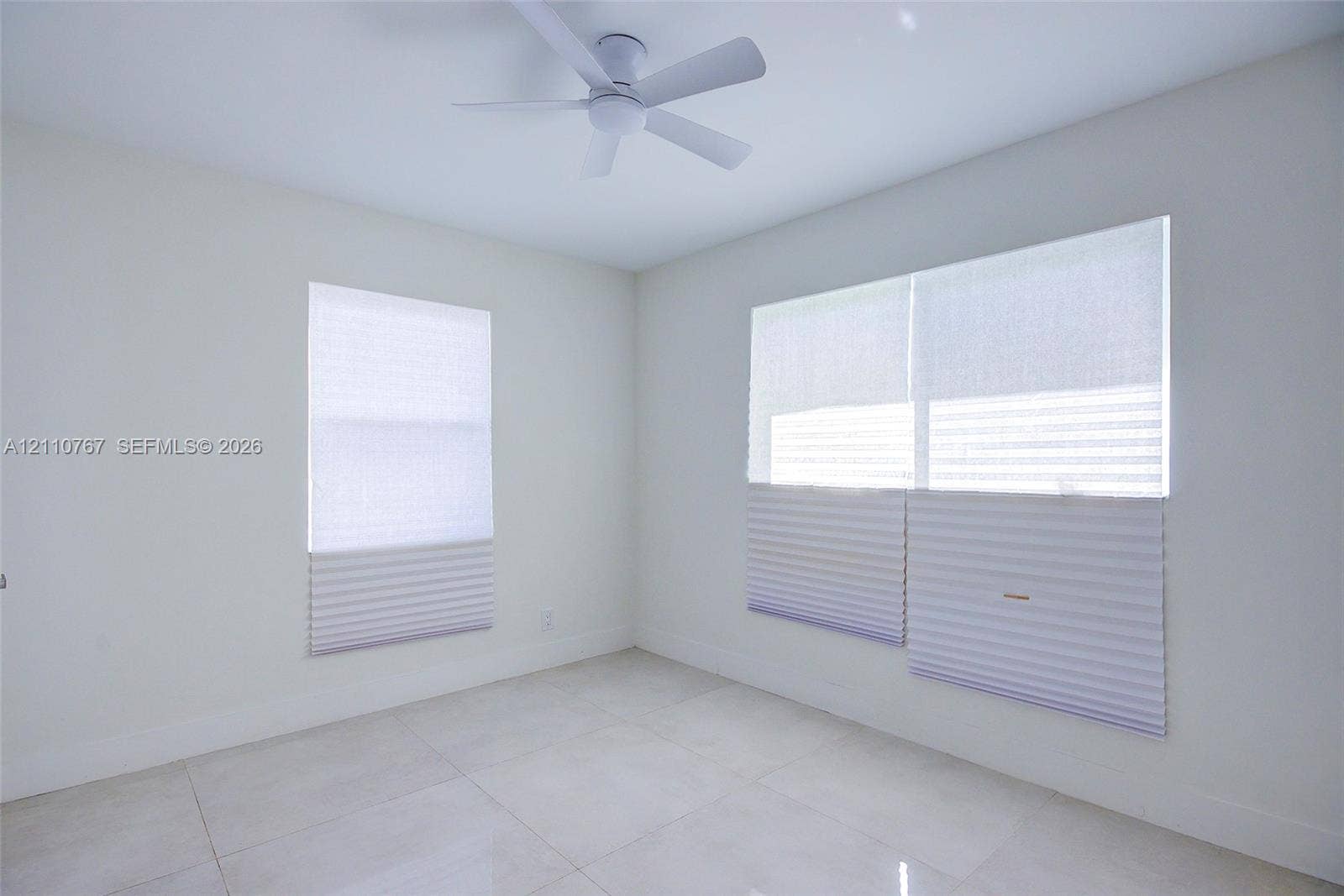 5305 Cleveland Road, Delray Beach, FL 33484 Neutral-toned room featuring large-format tile flooring, a contemporary ceiling fan, and dual windows equipped with cordless pleated shades