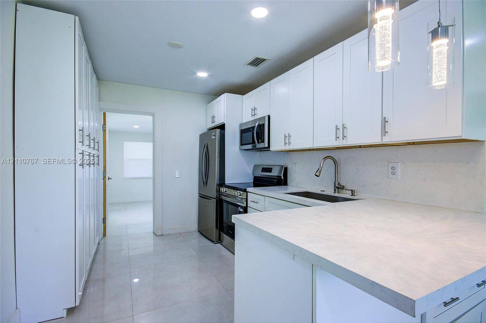 5305 Cleveland Road, Delray Beach, FL 33484 Kitchen featuring white shaker cabinetry, stone-finish countertops, stainless steel appliances, tile flooring, and glass pendant lighting
