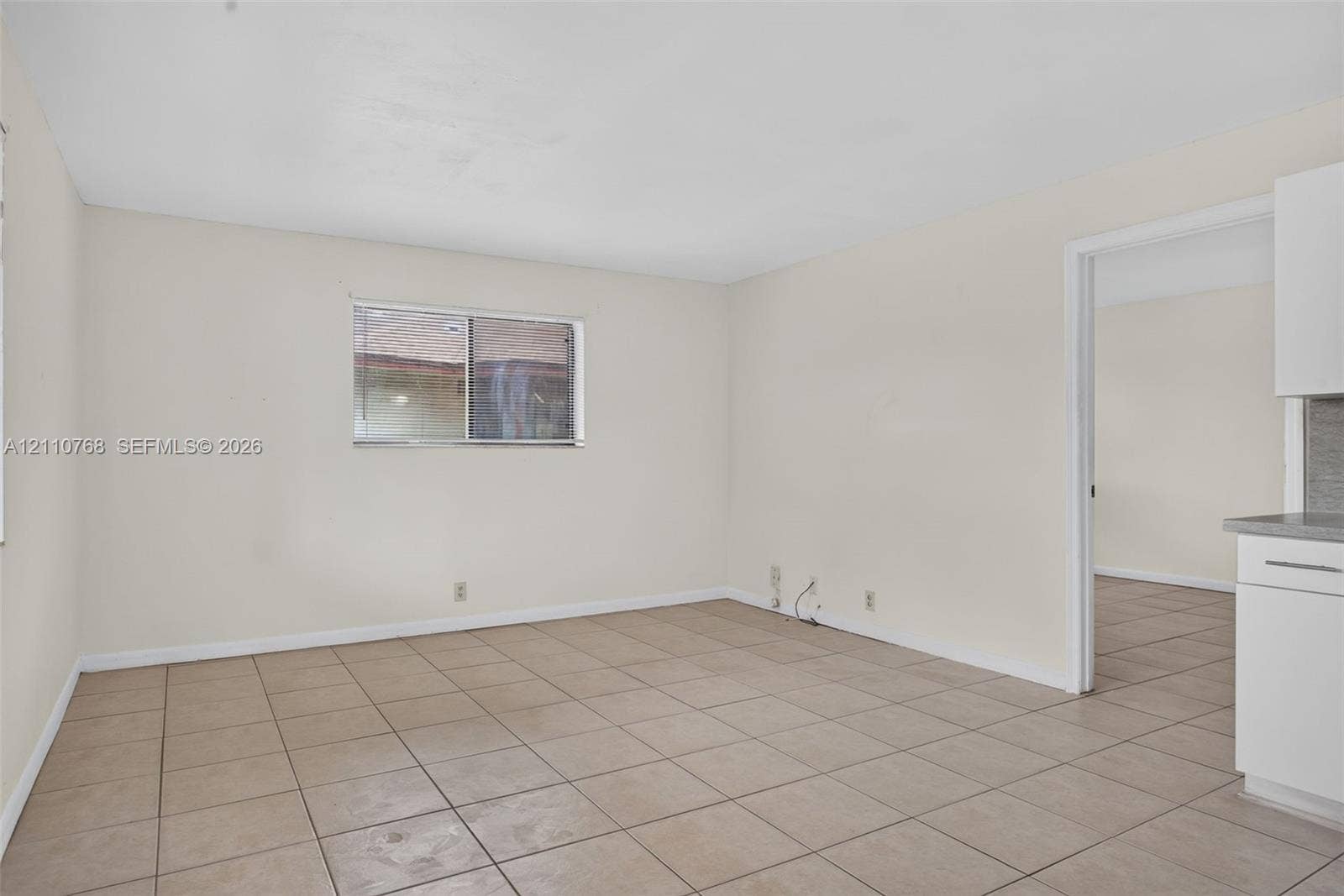 2070 NW 43rd Terrace, #7, Lauderhill, FL 33313 Neutral-toned interior space featuring light-colored wall finishes, ceramic tile flooring, and a sliding glass window