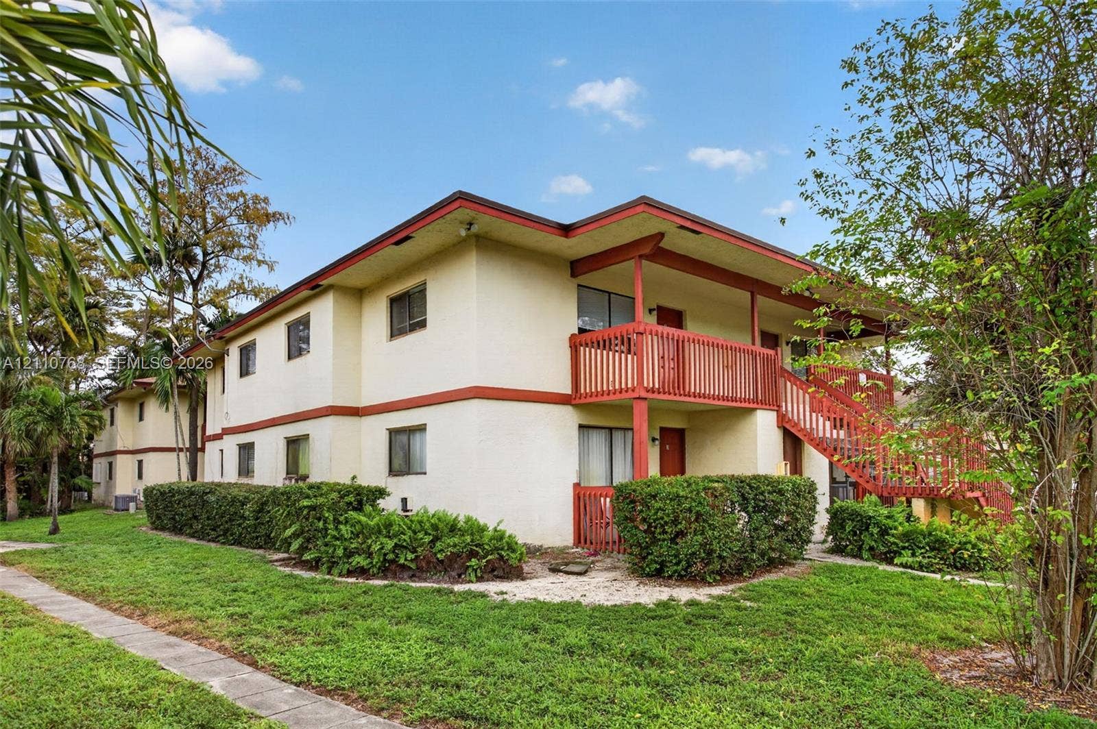 2070 NW 43rd Terrace, #7, Lauderhill, FL 33313 Two-story exterior featuring light-colored stucco siding, contrasting trim, an expansive wood-railing balcony, and a dedicated staircase