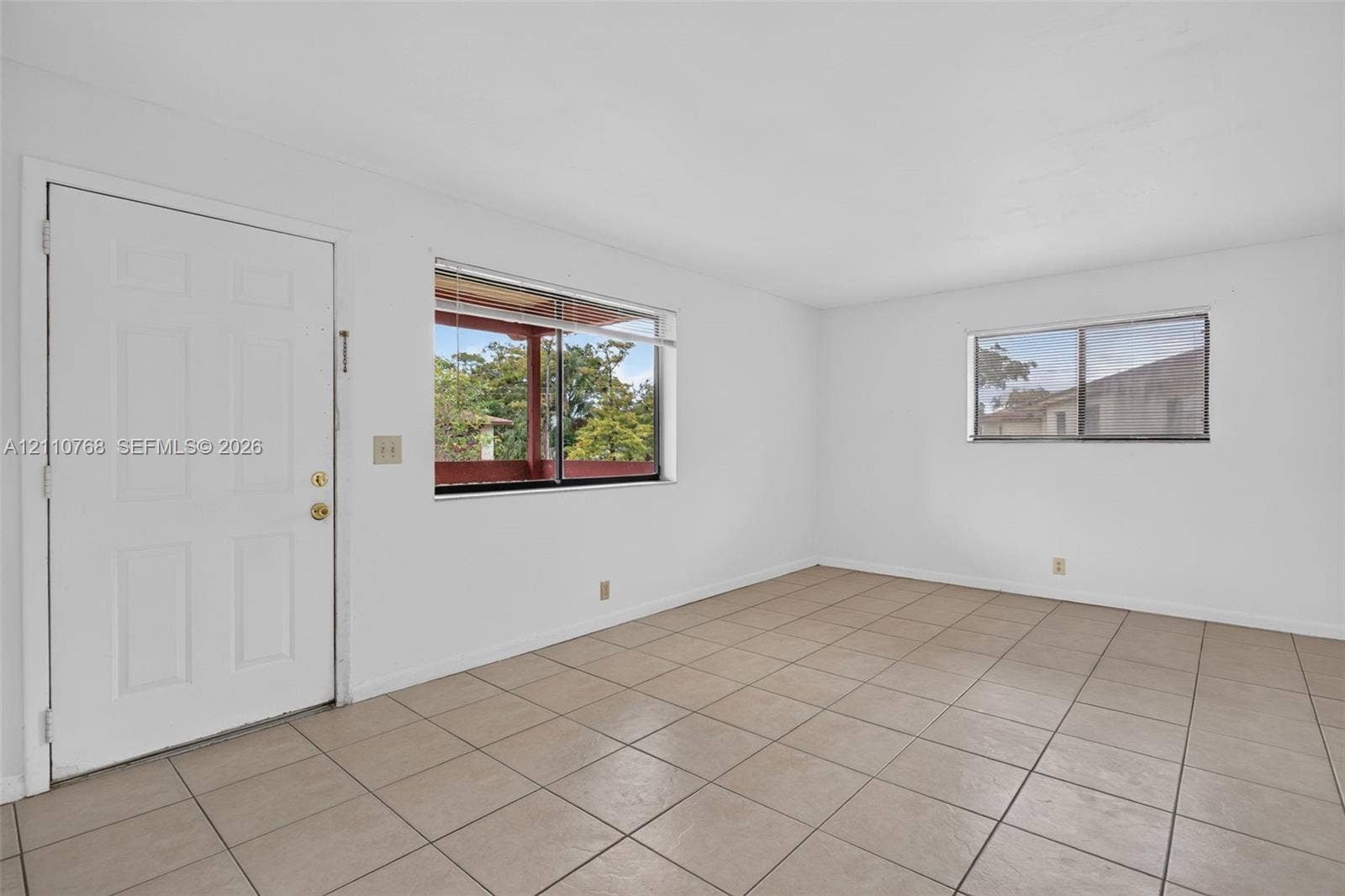 2070 NW 43rd Terrace, #7, Lauderhill, FL 33313 Neutral-toned square tile flooring, white wall surfaces, and two windows with horizontal blinds