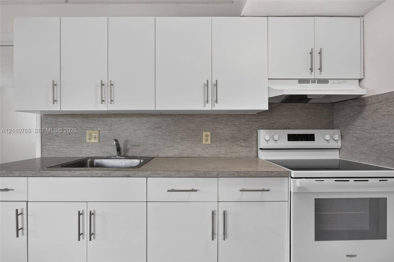 2070 NW 43rd Terrace, #7, Lauderhill, FL 33313 Kitchen featuring white flat-panel cabinetry, neutral stone-finish countertops, stainless steel sink with a metallic faucet, and a white electric range with a built-in range hood