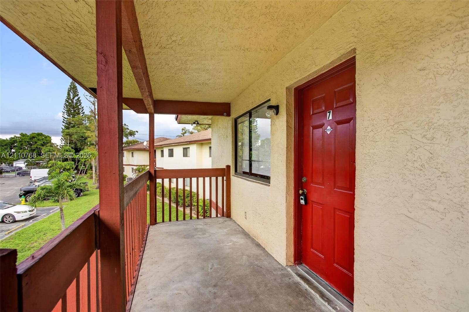 2070 NW 43rd Terrace, #7, Lauderhill, FL 33313 Covered exterior walkway featuring concrete flooring, a paneled door, and wood-style railing