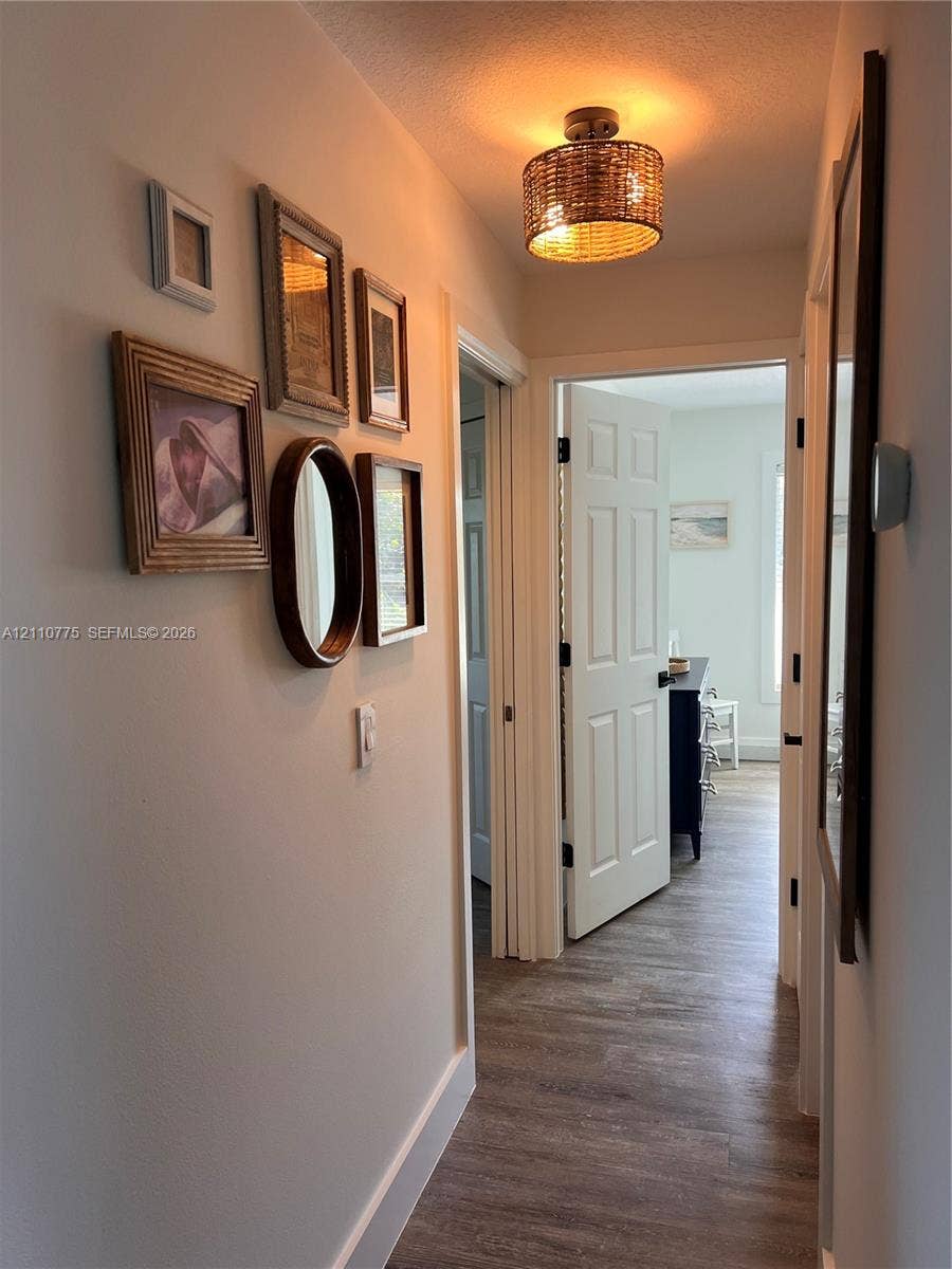 4995 S Highway A1a, #D, Melbourne Beach, FL 32951 Hallway featuring wood-finish flooring, a woven drum flush-mount light fixture, and six-panel interior doors with matte black hardware