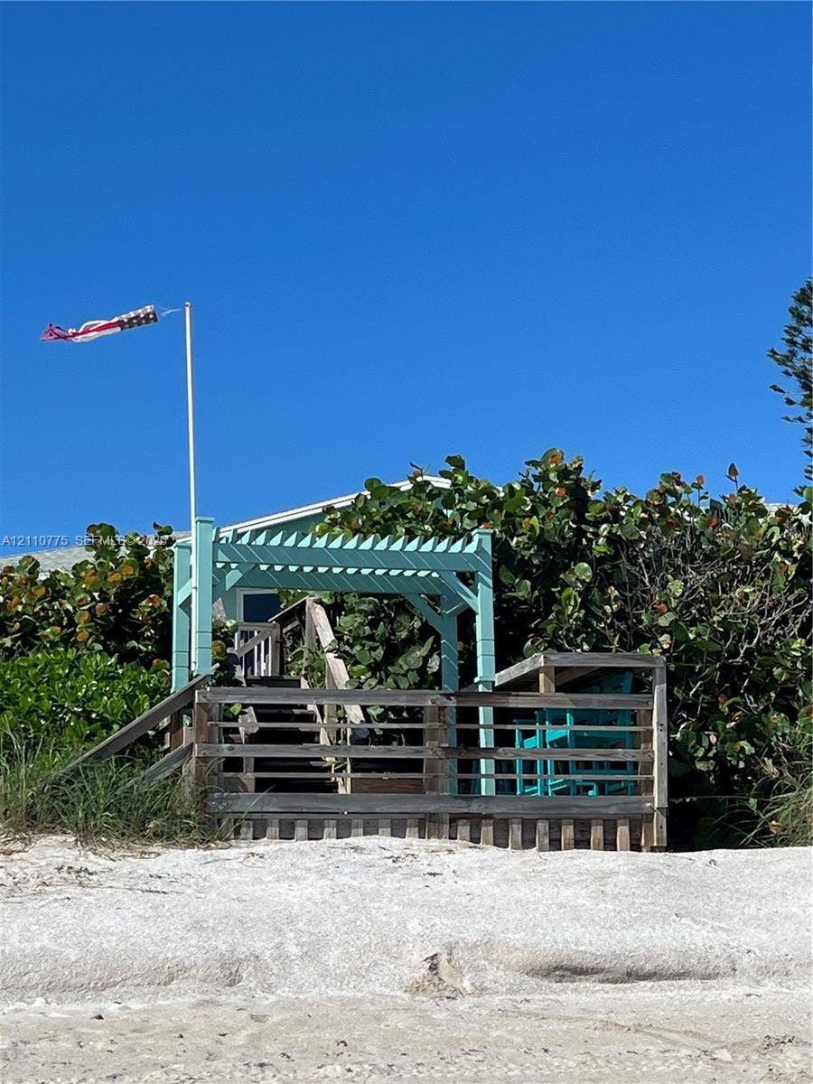 4995 S Highway A1a, #D, Melbourne Beach, FL 32951 Coastal wood deck featuring a painted pergola, stair access, and integrated railing