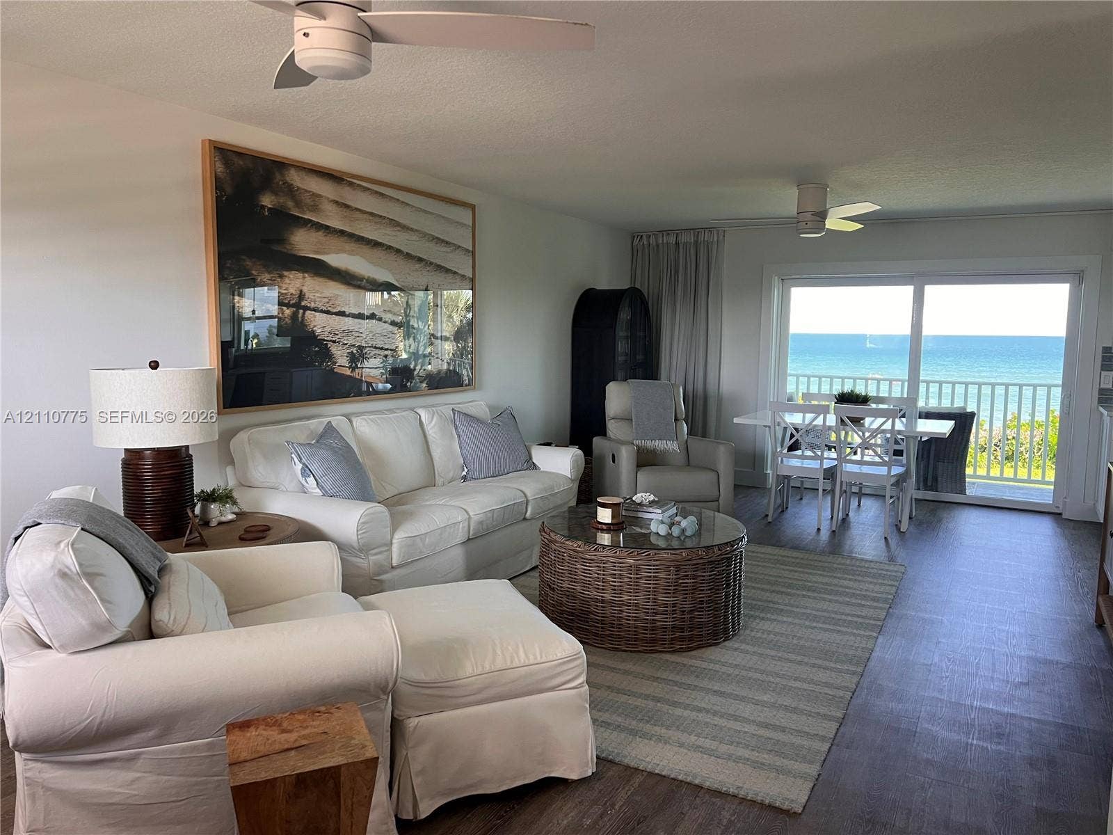 4995 S Highway A1a, #D, Melbourne Beach, FL 32951 Living area featuring wood-finish flooring, white ceiling fans, and sliding glass doors with direct access to an exterior balcony