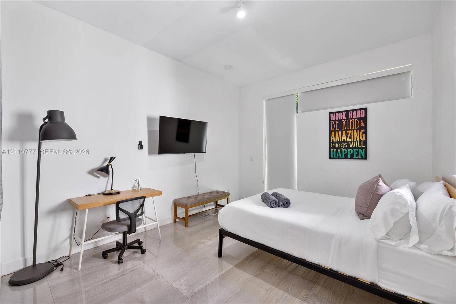 Neutral-toned tile flooring, high ceilings, and floor-to-ceiling roller shades
