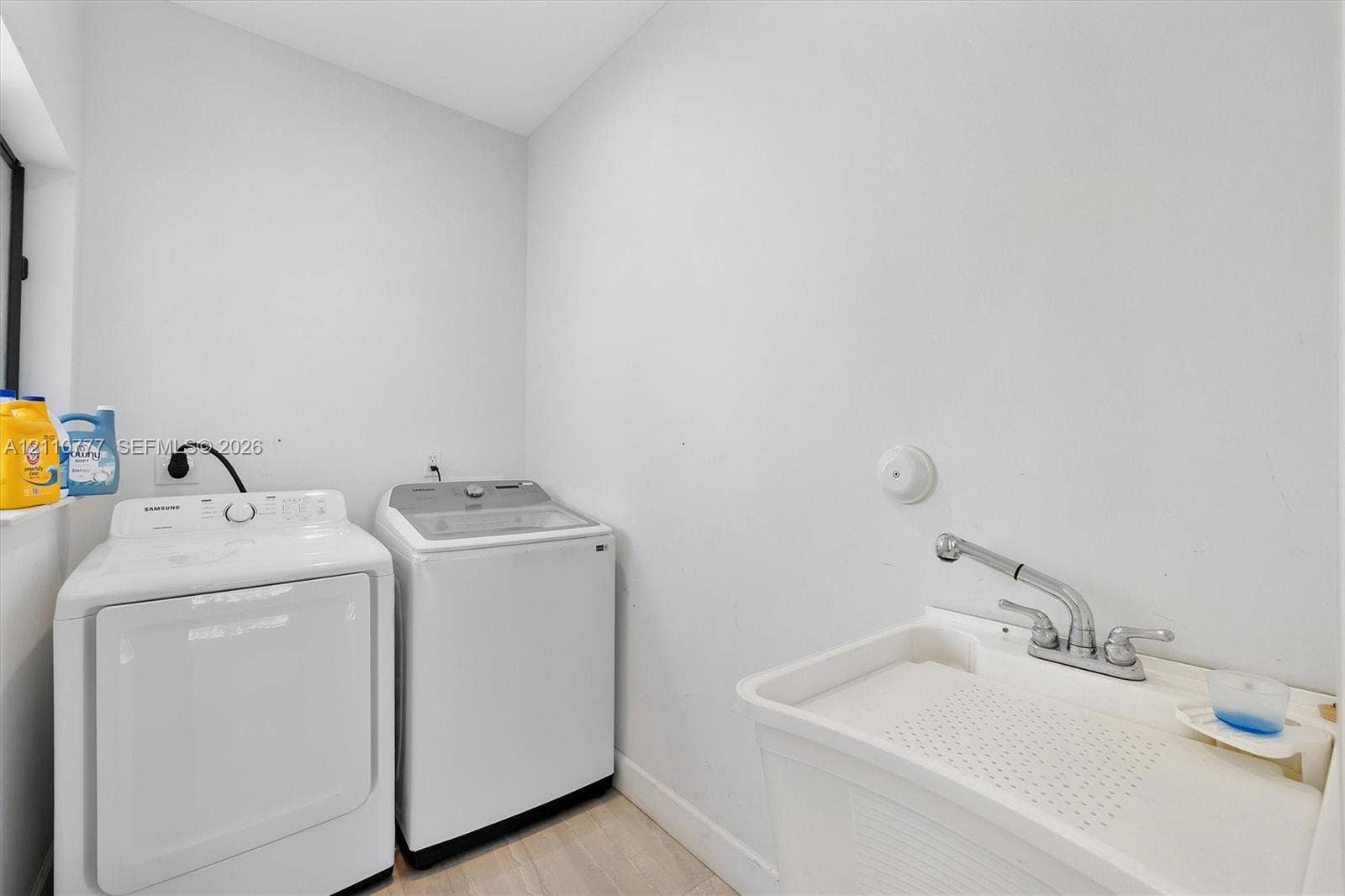 Utility space featuring a thermoplastic deep-basin sink, dual-handle faucet, and dedicated laundry hookups