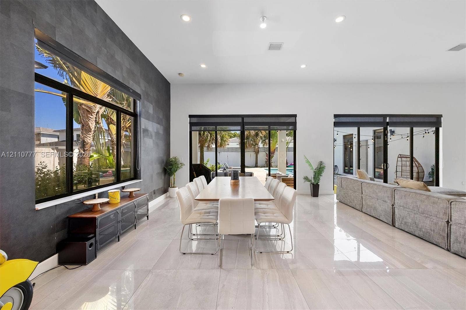 Spacious interior featuring large-format tile flooring, a charcoal-toned textured accent wall, recessed lighting, and multiple sliding glass door systems