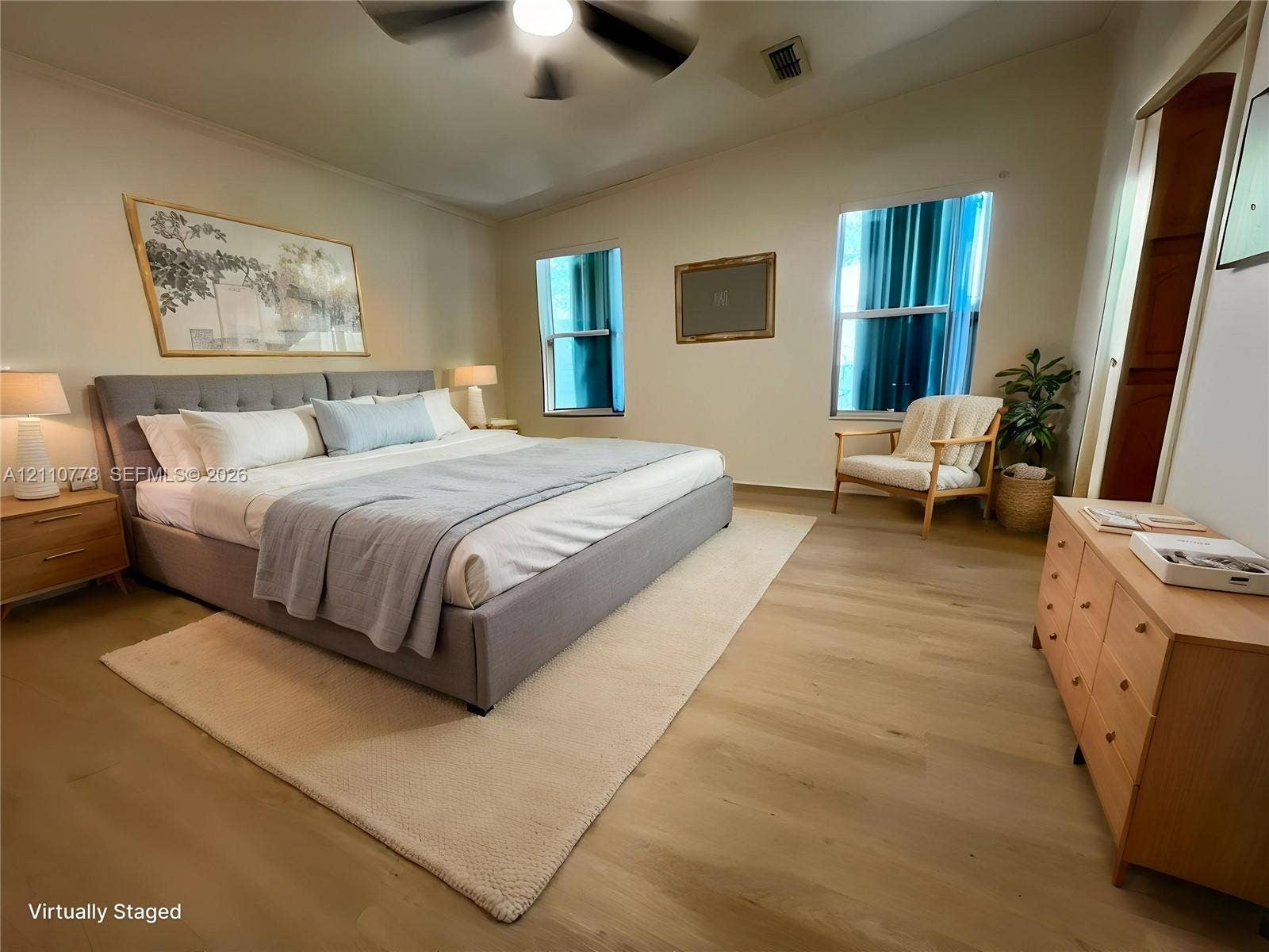 Spacious room featuring wood-finish flooring, dual windows, and an attached ceiling fan