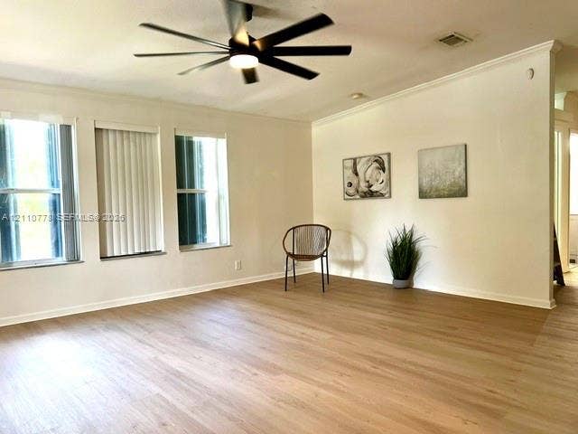 Neutral wall color, wood-finish flooring, multi-pane windows, crown molding, and a modern ceiling fan with integrated lighting