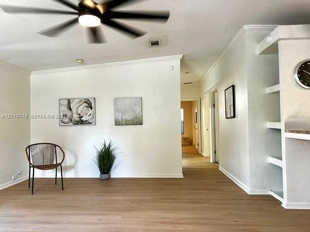Wood-finish flooring, ceiling fan with integrated lighting, and custom built-in shelving with stone-surface counter