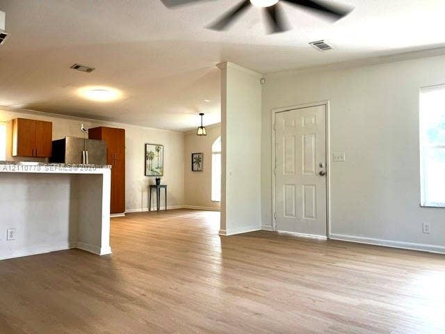 Open-concept living space featuring wood-finish flooring, a kitchen peninsula with countertop seating, and a ceiling fan