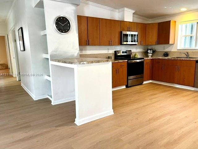 Kitchen featuring wood-finish cabinetry, stone-surface countertops, stainless steel appliances, and wood-finish flooring