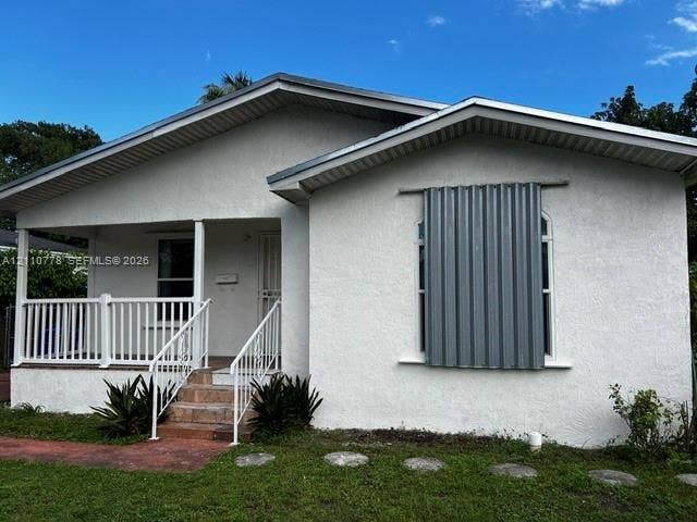 Stucco exterior with a covered front porch, white metal railing, and stone-tiled stairs