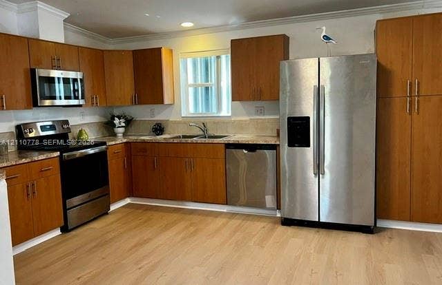 Kitchen featuring wood cabinetry, stainless steel appliances, stone-finish countertops, and wood-finish flooring