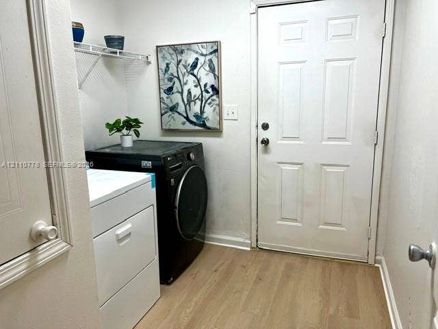 Utility space featuring wood-finish flooring, a wall-mounted wire shelving unit, and an exterior door with a deadbolt lock