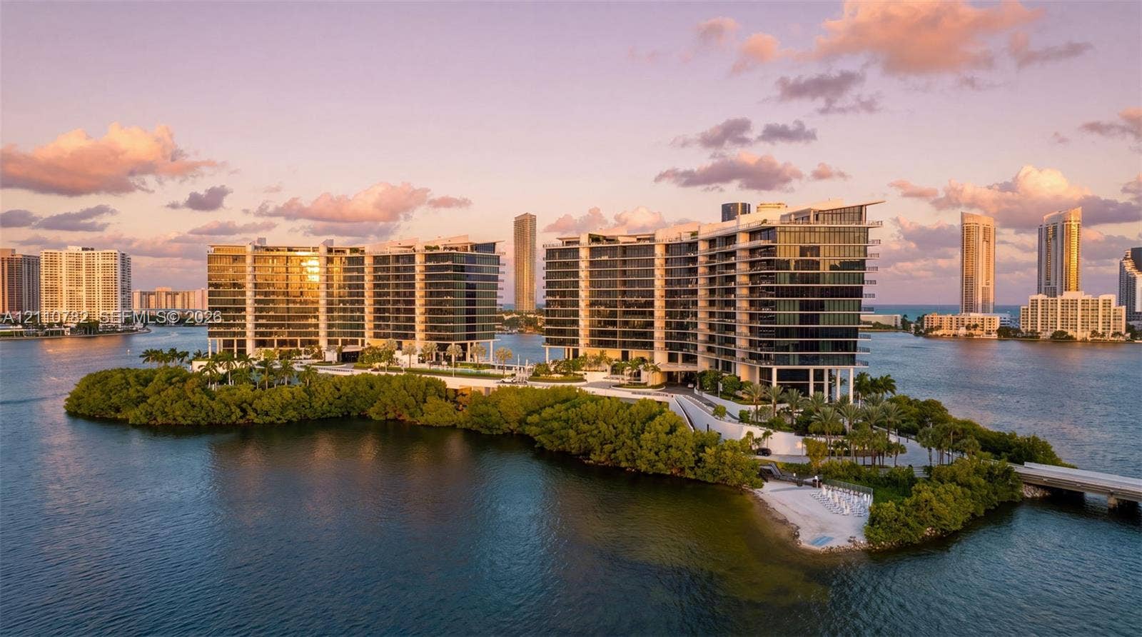 Waterfront residential complex featuring floor-to-ceiling glass facades, wraparound balconies, professional landscaping, and private island access