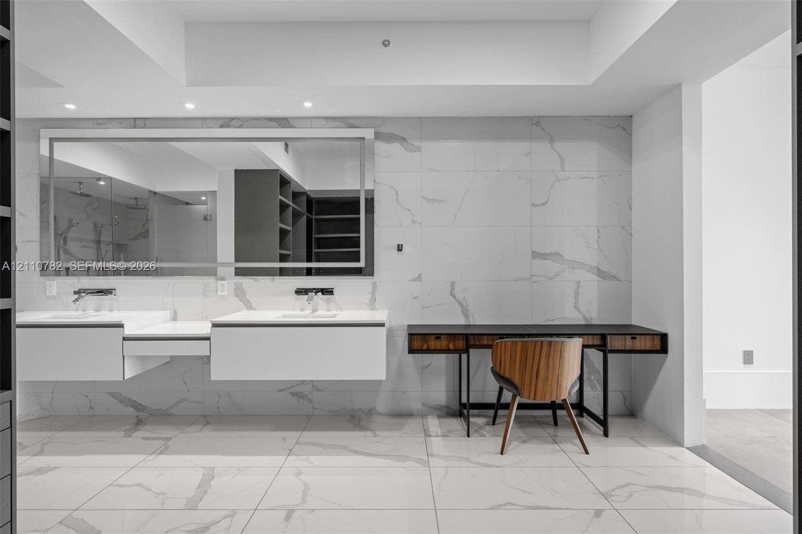 Floating dual vanity with integrated sinks, large-format stone-finish tile flooring and wall cladding, recessed lighting, and expansive wall-to-wall vanity mirror